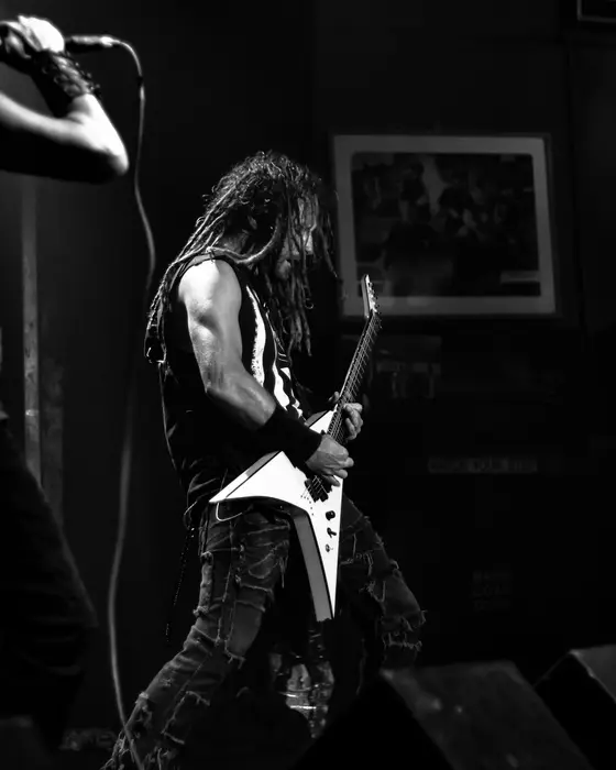 A singer with long hair at the microphone, a guitarist in front, in black and white.