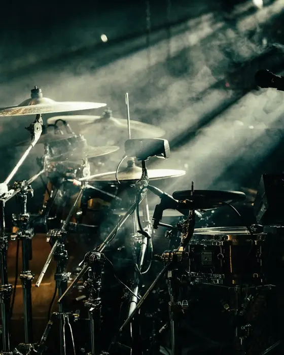 A drum kit in smoke and slanting stage light.